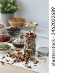 A vibrant and nutritious trail mix featuring goji berries, pumpkin seeds, sunflower seeds, chocolate-covered raisins, almonds, dried cranberries, cashews, and walnuts.