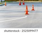 Vibrant orange traffic cones stand resolutely in a public parking lot, signaling caution and guiding drivers through a maze of potential hazards, reminding us to navigate safely