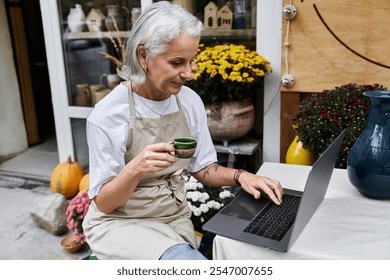 A vibrant outdoor space features a woman sipping coffee while typing on a laptop. - Powered by Shutterstock