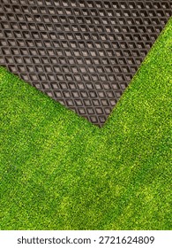 Vibrant patch of artificial turf bright green color contrasted with textured black rubber mat. Decorative background for design. Stylish and functional look, appealing aesthetic