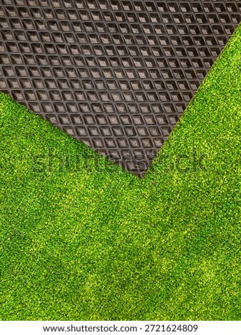 Vibrant patch of artificial turf bright green color contrasted with textured black rubber mat. Decorative background for design. Stylish and functional look, appealing aesthetic