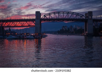 A vibrant pink sunset shining over the famous Burrard Street Bridge in Vancouver, Canada