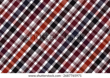 A vibrant plaid pattern features a mix of deep reds, blacks, and whites in a diagonal arrangement. The fabric exhibits a soft texture, creating a warm and inviting visual.