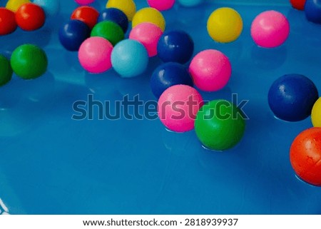 Vibrant plastic balls floating in clear blue pool water with copy space