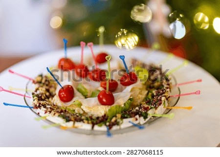 A vibrant plate of appetizers featuring cherry tomatoes on colorful heartshaped skewers is set against a blurred background of festive lights