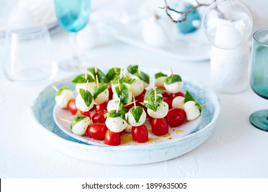 A Vibrant Plate Of Caprese Salad Bites. Bright Engaging Colours Of Red, White And Green Against A Pale Blue Backdrop. These Make The Perfect Appetiser, Fresh, Healthy, Homemade.