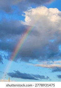 Vibrant Rainbow Emerging from Dramatic Storm Clouds in Blue Evening Sky