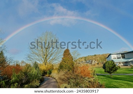 A vibrant rainbow graces the sky above RHS Garden, Harrogate,England, on a sunny winter day, adding ethereal beauty to the scene.