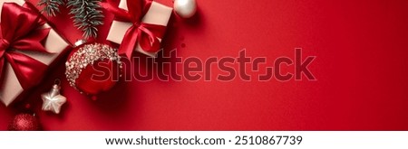 Vibrant red background adorned with golden gift boxes with red ribbons, Christmas ornaments, and pine branches. Perfect for holiday promotions, festive greetings, and seasonal decorations.