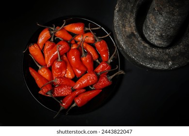 Vibrant Red Chili peppers in a rustic Pestle and Mortar in black background , Spicy peppers , 
Kerala Traditional top view side view black background, stone plate  - Powered by Shutterstock