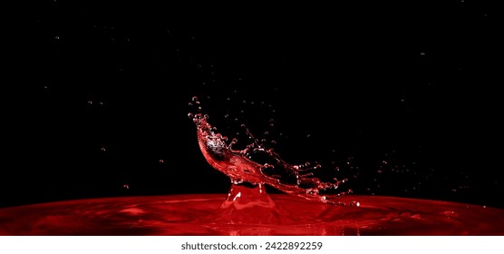 A vibrant Red liquid splashes forcefully into a body of water creating ripples and waves. 