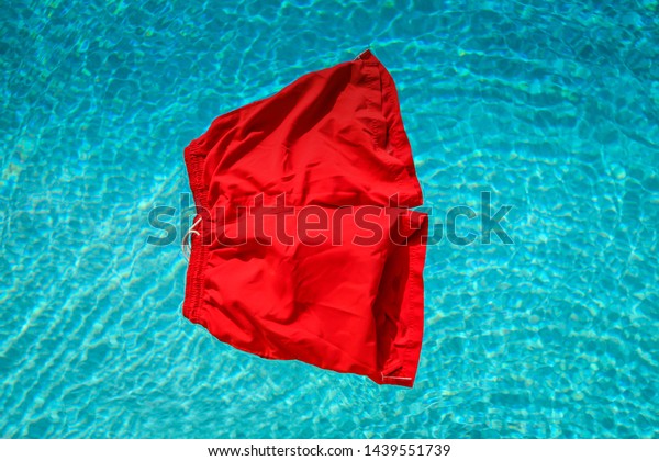 A
vibrant red pair of swimming shorts floating on a
pool