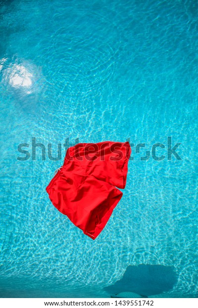 A\
vibrant red pair of swimming shorts floating on a\
pool