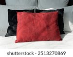 A vibrant red pillow is resting on a bed, positioned right next to a contrasting black pillow, creating a dynamic visual appeal