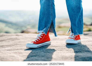 Vibrant Red Sneakers and Stylish Denim Jeans on Sunlit Rocky Terrain in Countryside - Powered by Shutterstock