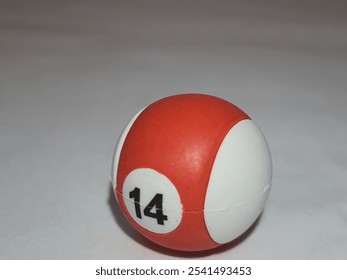 A vibrant red and white pool ball, number 14, sits on a plain white surface. - Powered by Shutterstock