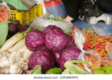 A vibrant scene at a traditional market showcasing fresh vegetables like purple cabbage, garlic, white radish, and red chili peppers. Perfect for content related to traditional markets, healthy eating - Powered by Shutterstock