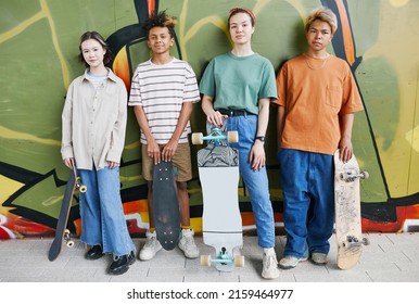 Vibrant shot of diverse group of teenagers with skateboards standing against graffiti wall and looking at camera in urban street setting - Powered by Shutterstock