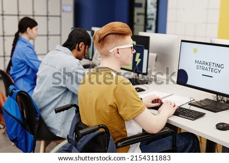 Vibrant shot of young people using computers in college library with focus on student with disability doing research