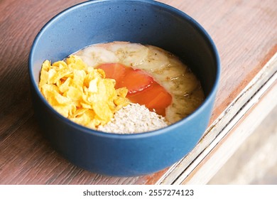 A vibrant smoothie bowl featuring a creamy blend of acai and tropical fruits, topped with banana slices, papaya chunks, cornflakes, and oats. A healthy and colorful dish perfect for breakfast  - Powered by Shutterstock