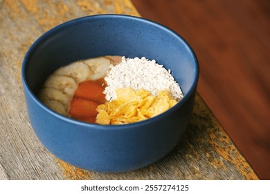 A vibrant smoothie bowl featuring a creamy blend of acai and tropical fruits, topped with banana slices, papaya chunks, cornflakes, and oats. A healthy and colorful dish perfect for breakfast  - Powered by Shutterstock