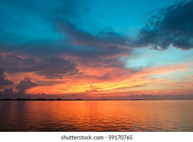 Vibrant sunset with clouds, blue sky background over water