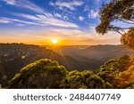 A vibrant sunset illuminates the iconic Three Sisters rock formation in the Blue Mountains National Park of Australia.