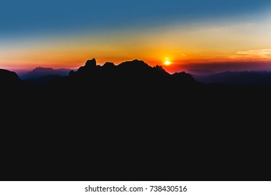 Vibrant sunset mountain background, silhouette of mountains with orange, yellow, purple and blue colours. Desktop wallpaper, animatioin, paint.