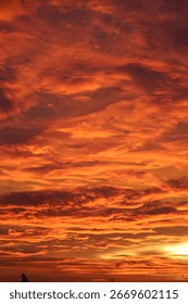 Vibrant sunset sky with dramatic orange and red clouds creating a fiery evening atmosphere. Natural background of colorful twilight sky
