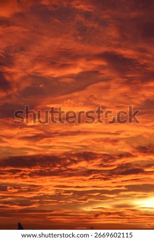 Vibrant sunset sky with dramatic orange and red clouds creating a fiery evening atmosphere. Natural background of colorful twilight sky

