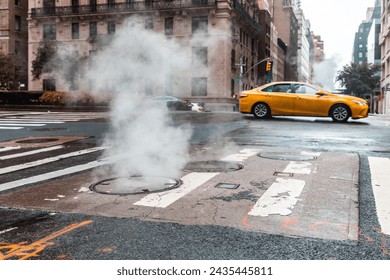 Vibrant urban street with steam rising from a manhole and a taxi in motion in New York - Steamy street scene with yellow taxi in the city - Powered by Shutterstock