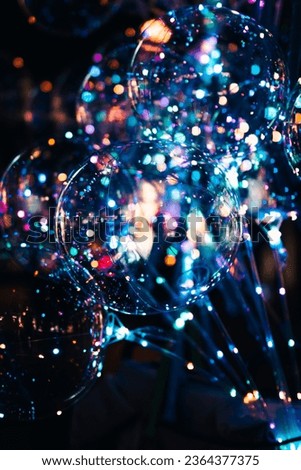 A vibrant vertical image of a selection of large, clear balloons adorned with multicolored lights