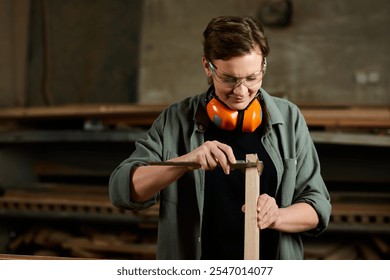 In a vibrant workshop, a female carpenter meticulously shapes wood while wearing safety gear, focused on her craft. - Powered by Shutterstock