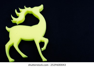 A vibrant yellow deer with prominent antlers stands out beautifully against a solid black background, creating a striking visual contrast - Powered by Shutterstock