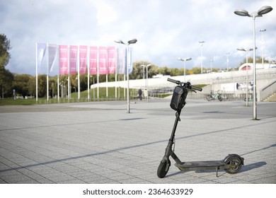 A vibrant yellow scooter parked on a rough stone pavement in a cityscape illuminated by bright street lights - Powered by Shutterstock