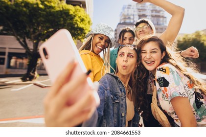 Vibrant young people taking a selfie together. Cheerful generation z friends having fun while hanging out together in the city. Multiethnic group of friends capturing their happy moments in the sun. - Powered by Shutterstock