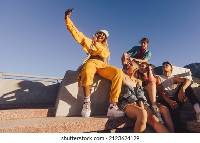 Vibrant Young People Taking A Selfie Together Outdoors. Happy Youngsters Enjoying Hanging Out Together In The City. Group Of Generation Z Friends Capturing Their Happy Moments.