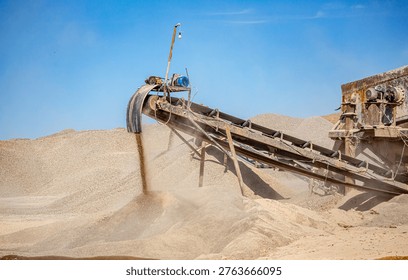 Vibrating screen stone crusher in operation. Crushing stones in a quarry for processing minerals, cement, limestone. Heavy and mobile equipment in a quarry for processing stone into building material.