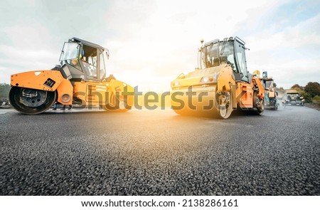 Vibratory asphalt rollers compactor compacting new asphalt pavement. Road service repairs the highway