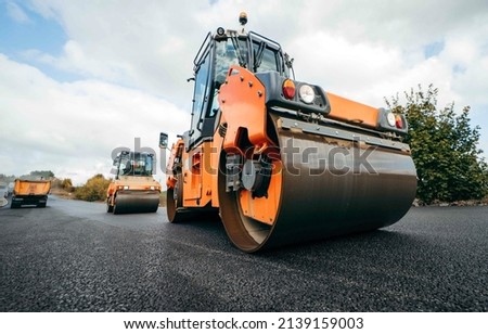 Vibratory asphalt rollers compactor compacting new asphalt pavement. Road service build a new highway