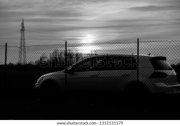 VICENZA, ITALY - January 28, 2019:\
White hatchback car VW Golf park behind a metal net with the\
sunshine in a background. Color toning modified in\
post-production.