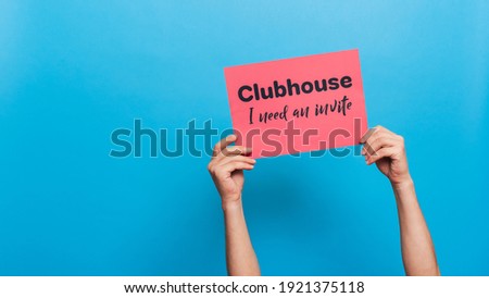 VICHUGA, RUSSIA - FEBRUARY 20, 2021: Men's hands hold a banner asking them to invite his to trendy social media app Clubhouse