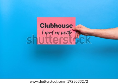 VICHUGA, RUSSIA - FEBRUARY 20, 2021: man's hand holds a banner with a call to invite him to trendy social networking and communication app Clubhouse on a bright colored background
