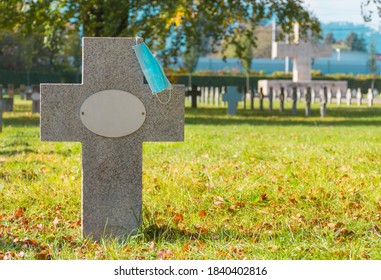 Victim Of Coronavirus Covid 19 Conceptual Photo With Protective Medical Mask On A Stone Tomb In The Cemetery