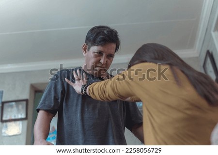A victimized woman tries to push away her angry and unhinged husband. Example of conflict and physical abuse in intimate relationships.