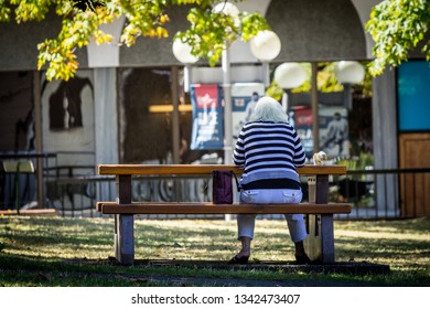 Victoria, BC, Canada, Fall, 2015.  Rear View Of Woman In Striped Top Sitting At A Picnic Table