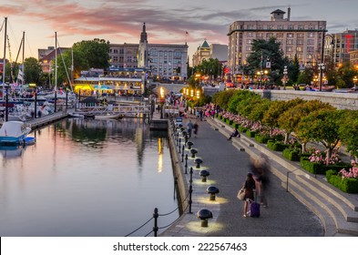 Victoria, BC, Canada - July 4, 2014: Inner Harbour Pathway At Sunset Crowded With People In Motion. This Patch Of Waterfront Is The Location Of Many Tourist Attractions And Recreational Activities. 