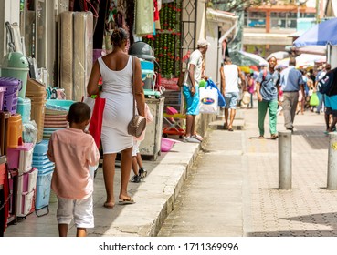 Victoria, Seychelles - January 6, 2020: Creole Mother With Kids Walking On The Street With Shops At Victoria City.