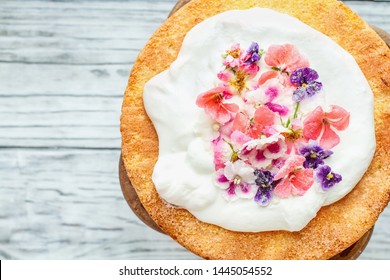 Victoria Sponge Cake With Whipped Cream And Sugared Flowers Over A White Wooden Rustic Table Top. Image Shot For Above.