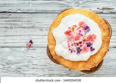 Victoria Sponge Cake With Whipped Cream And Sugared Flowers Over A White Wooden Rustic Table Top. Image Shot For Above.